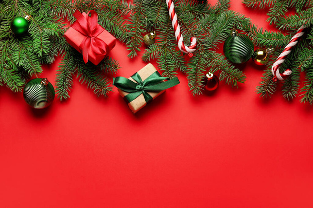 Kompozycja z gałązek jodły, prezenty świąteczne i dekoracje na czerwonym tle - Zdjęcie, obraz
