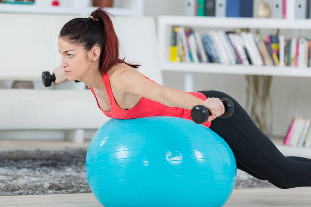 young sportswoman doing exercises with ball and dumbbells - Foto, Imagem