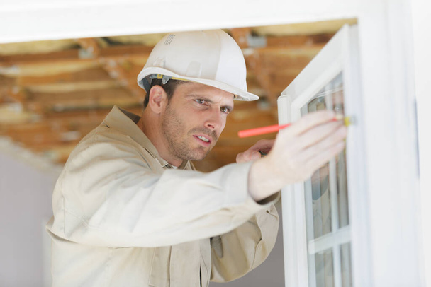male builder measuring a window - Фото, зображення