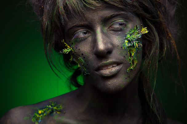 Nainen, jolla on mustat kasvot ja vihreä kasvotaide
 - Valokuva, kuva