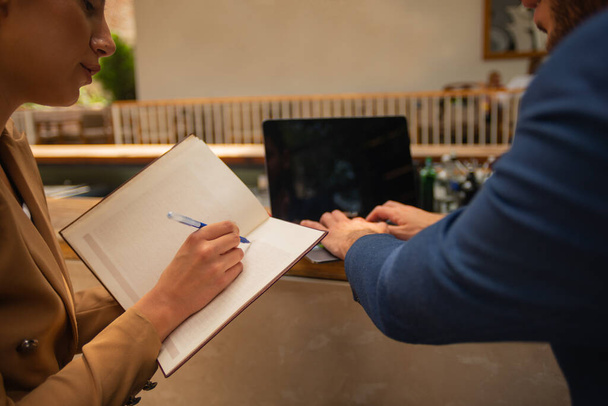Um jovem homem de negócios deu uma olhada no caderno de seu colega feminino enquanto ele está trabalhando em seu colo - Foto, Imagem