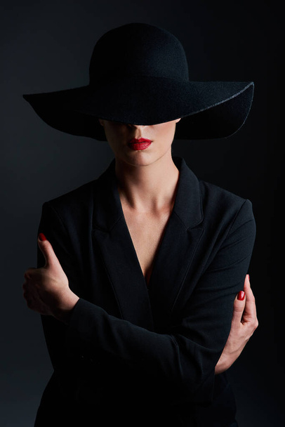 All things unrevealed belong to the kingdom of mystery. Studio shot of a beautiful mature woman wearing a hat and posing against a dark background - Zdjęcie, obraz
