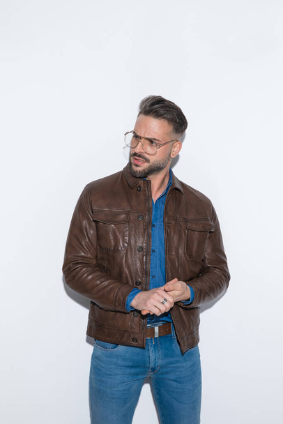 Young handsome casual man with attitude is rubbing his palms and looking away against white studio background - Photo, Image