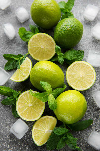 Lime and mint on a dark background. The ingredients for making refreshing drinks and cocktails. - Фото, зображення