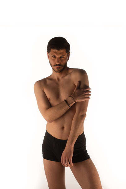 Hombre atractivo y sexy en el estudio haciendo poses seductoras y tocándose a sí mismo - Foto, Imagen