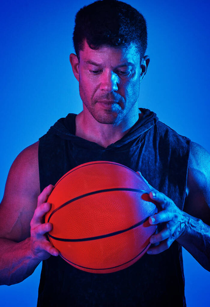 Shoot your shot. Blue filtered shot of a sportsman posing with a basketball in the studio - Фото, изображение