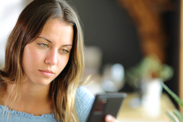 Young woman using smart phone sitting in a restaurant or home - Photo, Image