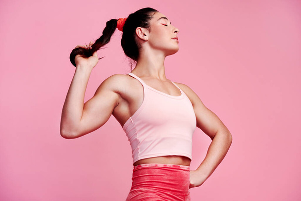 Je stärker dein Geist, desto stärker dein Körper. Studioaufnahme einer sportlichen jungen Frau, die ihren Pferdeschwanz vor rosa Hintergrund hält - Foto, Bild