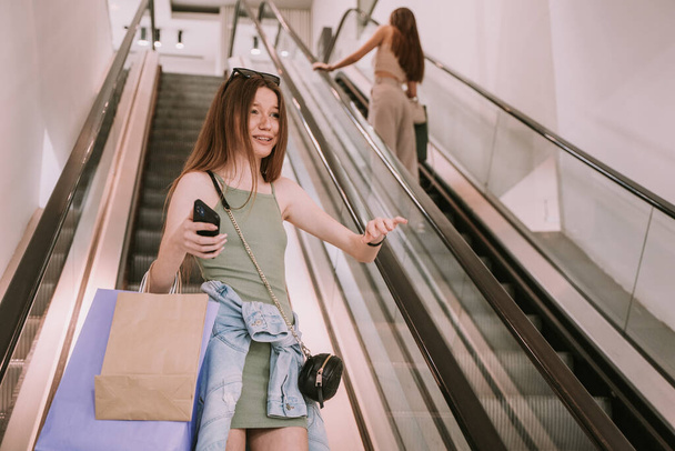 Young beautiful girl being happy because she met her friend on the escalator - Фото, зображення