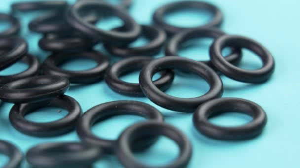 Black sealing rubber gaskets on colored blue background. Hydraulic spare parts. Rotation. Macro - Footage, Video