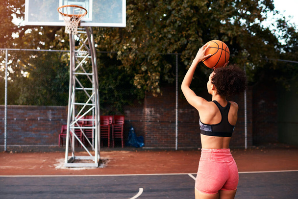 A entrar em algumas cenas de treino. Tiro de comprimento total de uma jovem esportista atraente sozinha em um campo de basquete e aquecendo com a bola - Foto, Imagem