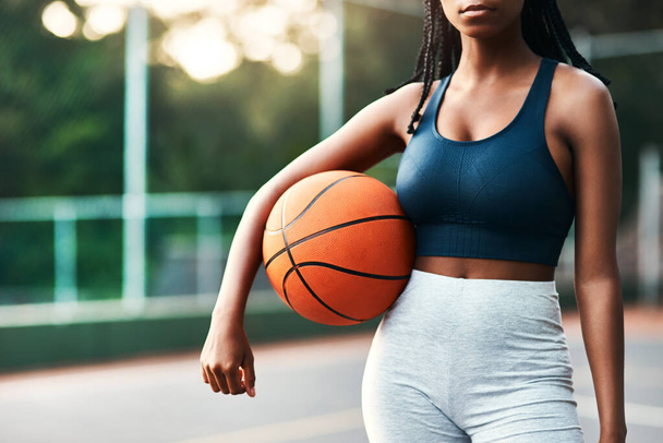 I am nothing without basketball. an unrecognizable sportswoman standing on the court alone and holding a basketball during the day - 写真・画像