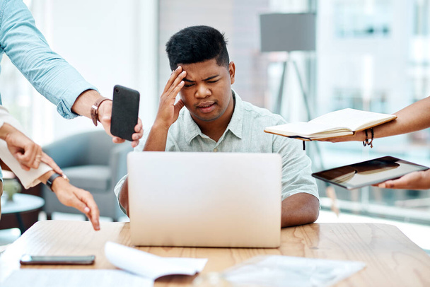 Being overwhelmed at work can hurt your productivity and your health. a young businessman looking stressed out in a demanding office environment - Zdjęcie, obraz