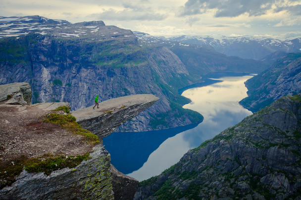 A vibrant picture of famous norwegian hiking place - trolltunga, the trolls tongue, rock skjegedall, with a tourist, and lake ringedalsvatnet and mountain panoramic scenery epic view, Norway - Фото, изображение