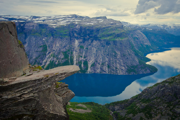 A vibrant picture of famous norwegian hiking place - trolltunga, the trolls tongue, rock skjegedall, with a tourist, and lake ringedalsvatnet and mountain panoramic scenery epic view, Norway - Valokuva, kuva