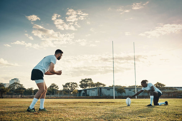 Hes about to kick like never before. Full length shot of two young rugby players training together on the field during the day - Photo, Image