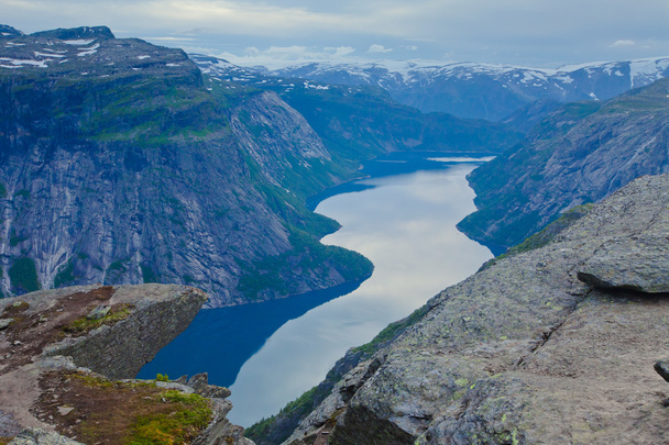 A vibrant picture of famous norwegian hiking place - trolltunga, the trolls tongue, rock skjegedall, with a tourist, and lake ringedalsvatnet and mountain panoramic scenery epic view, Norway - Foto, imagen