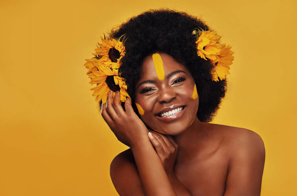 A virágok annyira felvidítanak. Stúdió portré egy gyönyörű fiatal nő mosolyog, miközben pózol napraforgóval a hajában ellen mustár háttér - Fotó, kép