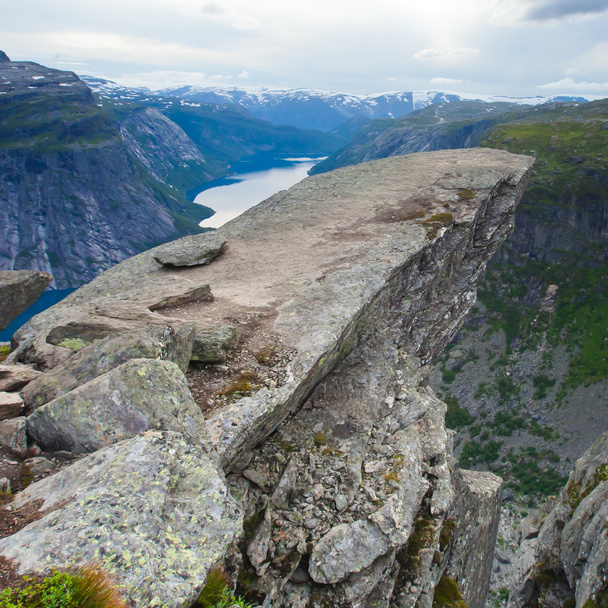A vibrant picture of famous norwegian hiking place - trolltunga, the trolls tongue, rock skjegedall, with a tourist, and lake ringedalsvatnet and mountain panoramic scenery epic view, Norway - Fotó, kép