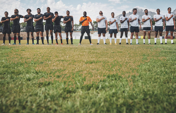 Κάποιες παραδόσεις το αξίζουν. δύο ομάδες ράγκμπι με αυτοπεποίθηση που στέκονται προσοχή τραγουδώντας τον ύμνο τους έξω σε ένα γήπεδο πριν από έναν αγώνα ράγκμπι. - Φωτογραφία, εικόνα