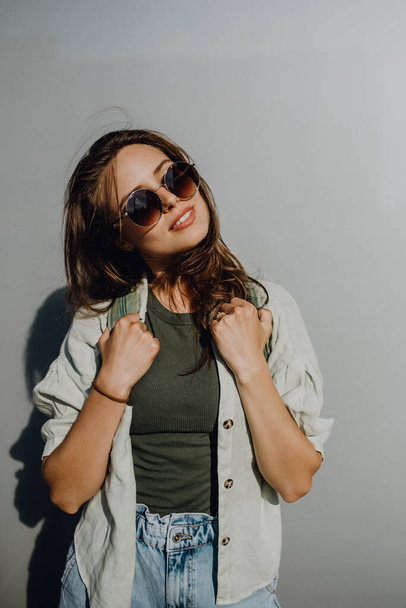 Portrait of happy young woman outdoor with a backpack and sunglasses. - Photo, image
