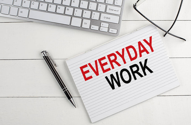 Текст EVERYDAY WORK на блокноті з клавіатурою, окуляри для ручок на білому дерев'яному фоні
 - Фото, зображення