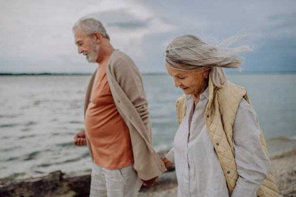 Senior couple relaxing and having romantic moment at the autumn sea. - Foto, afbeelding
