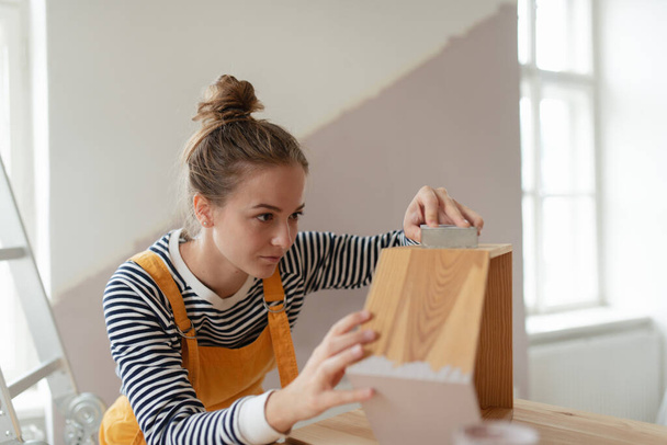 Portrait of young woman remaking shelf in her house. Concept of reusing materials and sustainable lifestyle. - Foto, Imagen