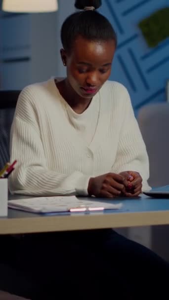 Ritratto di donna di colore di affari che guarda la macchina fotografica sorridere alzando la testa dal computer portatile che lavora nella società finanziaria start-up a tarda notte. Dipendente concentrato che fa gli straordinari rispettando la scadenza del progetto - Filmati, video
