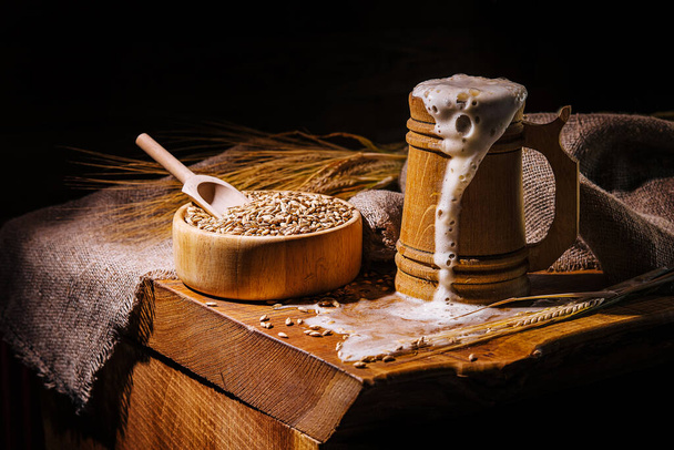 Wooden beer mug with beer and foam standing on a wooden table - Photo, Image
