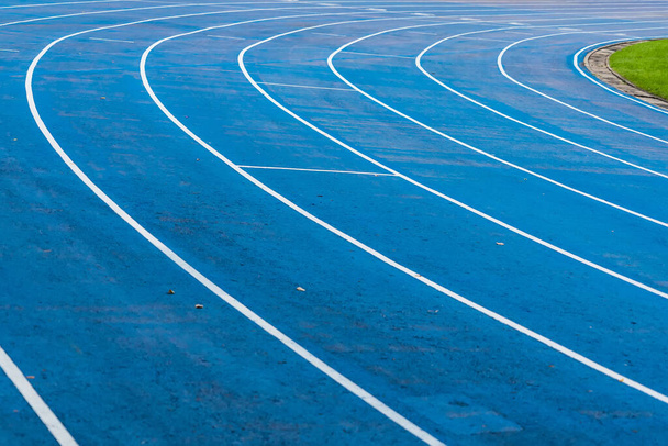 фон синей дорожки для соревнований по бегу на стадионе, фокус в центре. - Фото, изображение