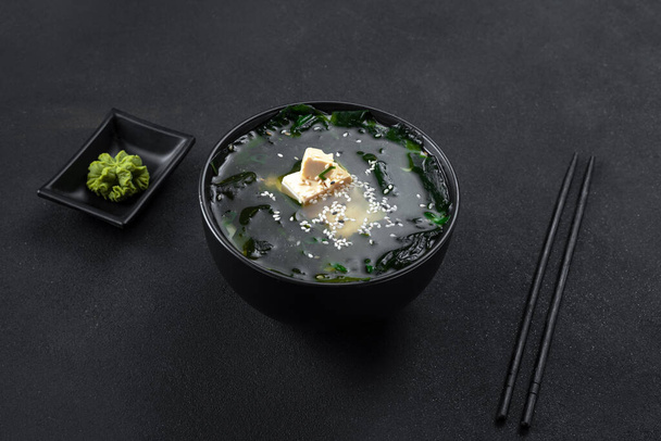 Asian food. Soup on a black background in a black bowl. - Photo, Image