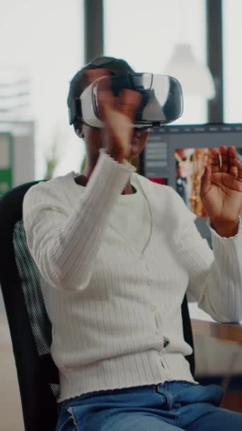 Afrikanischer Videobearbeiter erlebt VR-Brillen, gestikuliert, bearbeitet Videomontage mit Filmmaterial und Ton am Computer mit zwei Displays. Videograf bearbeitet Film in Kreativagentur - Filmmaterial, Video