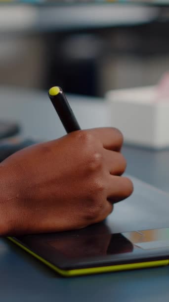Lähikuva kädessä afrikkalainen kuvaeditori piirustus graafinen tabletti muokkaamalla asiakkaan valokuvan tietokoneella, jossa on kaksi näyttöä. Musta korjaaja tilalla stylus kynä korjailua varat luova toimisto - Materiaali, video