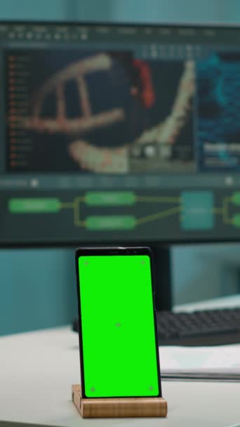 Pystysuora video: Näytä puhelin vihreällä näytöllä, mallintaa työpöydälle asetettua mallia tieteellisessä laboratoriossa, kun taas lääketieteellisten tutkijoiden ryhmä analysoi viruksen kehitystä digitaalisessa monitorissa - Materiaali, video