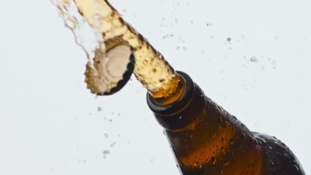 Cider splashing misted flask closeup. Drops trickle down beer bottle. Cold fresh lager beverage foaming fountaining at white background. Unfiltered alcohol carbonated liquor pouring out slow motion - Footage, Video