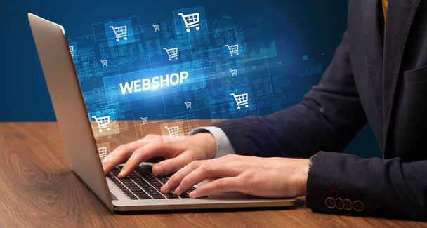 Businessman working on laptop with WEBSHOP inscription, online shopping concept - Foto, Imagen