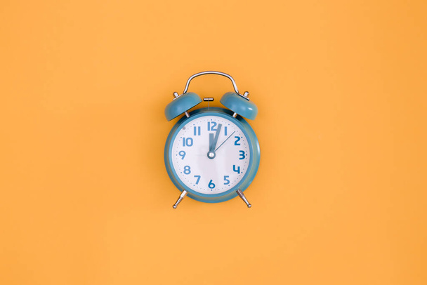 Reloj despertador azul sobre fondo naranja aislado, plano, minimalismo conceptual. - Foto, imagen