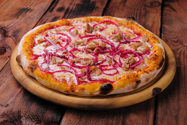 Ton balıklı pizza ve ahşap kesim tahtasında kırmızı soğan. - Fotoğraf, Görsel