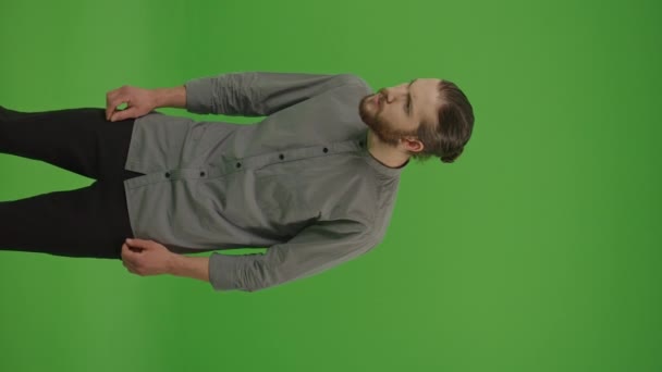 Video verticale, Vista verticale. Giovane studente freelance barbuto uomo in camicia denim emotivamente reagendo su qualcosa di spiacevole, forte, spaventoso e terribile su schermo verde, Chroma Key - Filmati, video