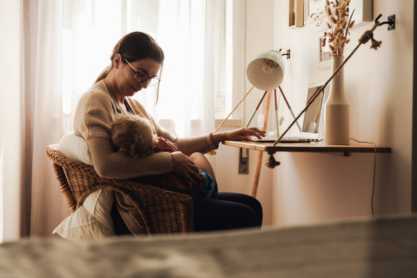 Busy woman working at home with a baby in the la - Foto, Imagen