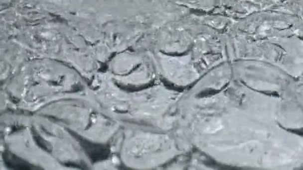 Primeros planos de hielo burbujeante vaso de agua. Cóctel orgánico de textura líquida ondulante en fondo blanco cáliz limpio. Artículos de vidrio acuático mineral girando en cámara lenta. Frescura concepto de estilo de vida saludable  - Imágenes, Vídeo