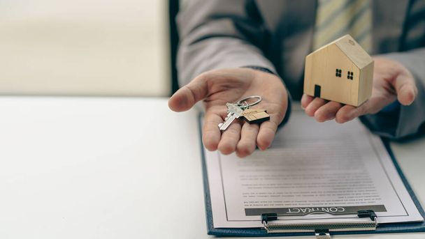 Los representantes de ventas reparten las llaves de la casa a los clientes después de firmar un contrato para comprar una casa o alquilar una nueva casa en la mesa. concepto de comprar una casa - Foto, imagen
