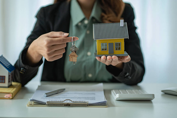 Satış temsilcileri, bir ev satın almak veya masada yeni bir ev kiralamak için bir sözleşme imzaladıktan sonra ev anahtarlarını müşterilere dağıtırlar. ev satın alma kavramı - Fotoğraf, Görsel