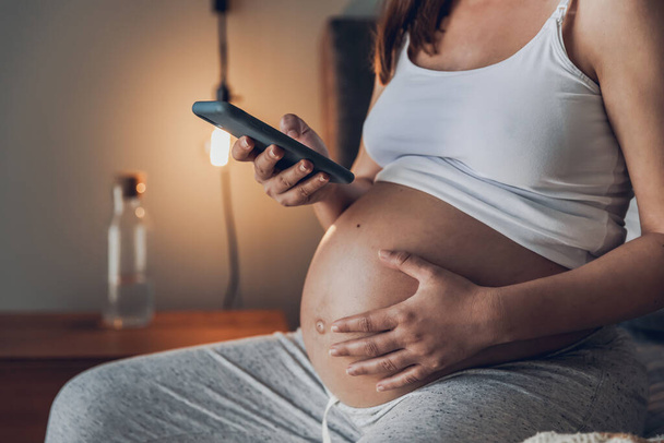 Painful pregnant young woman at home calling medical assistance on phone  - Foto, immagini