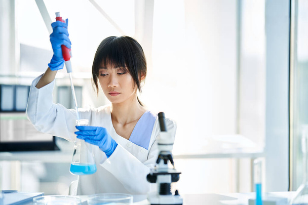 Asian scientist working in big modern laboratory doing some research. Medicine, microbiology, biotechnology concept - Foto, immagini