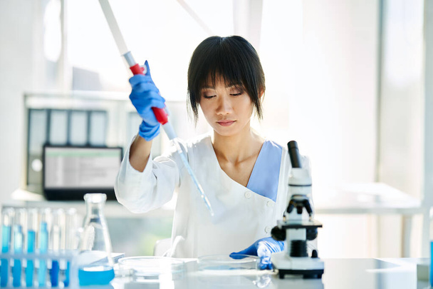 Azjatycki naukowiec pracujący w nowoczesnym laboratorium. Medycyna, mikrobiologia, koncepcja biotechnologii - Zdjęcie, obraz