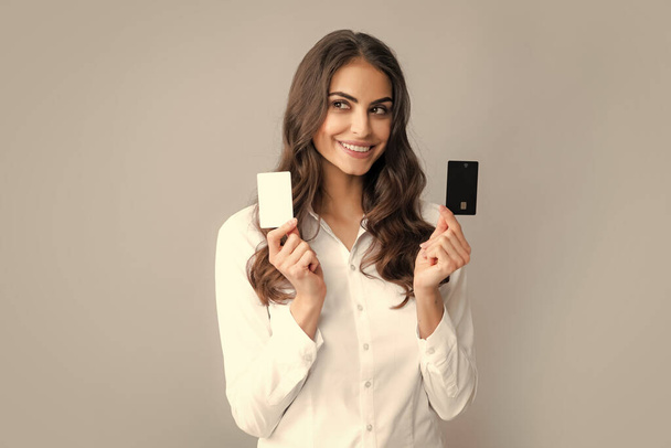 Fröhlich aufgeregt überraschte junge Frau mit Kreditkarte vor grauem Hintergrund - Foto, Bild