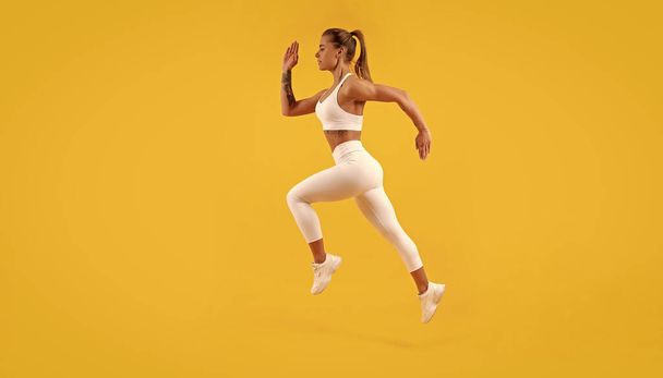 active fitness woman runner running on yellow background. - Foto, immagini