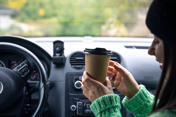 Road Trip Concept. Zadní pohled, dáma s šálkem kávy, sedící uvnitř auta. - Fotografie, Obrázek